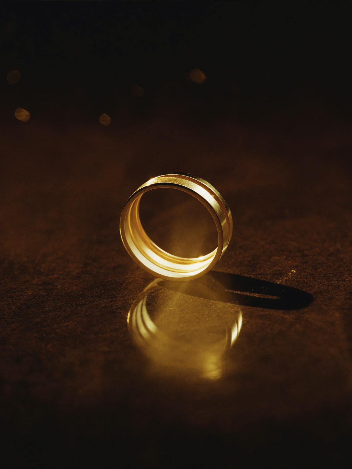 Study of a gold ring catching warm light on dark stone